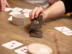 Photo of a white person's hand taking a card from a pile of 21X cards. Some other cards are face-up on the table, and there are also snacks
