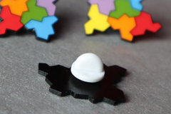 Photo of one of the pins face down on the table; the pin has a white rubber backing over the pointy bit