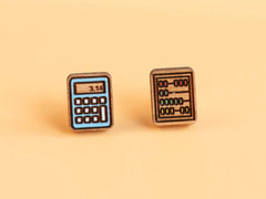 Photo of the 'abacus calculator' style earrings, which are both made from rounded rectangular pieces of wood, one etched with a calculator hand painted light blue showing '3.154' on the screen, and the other showing an abacus with red, blue, green and yellow beads on four horizontal bars.