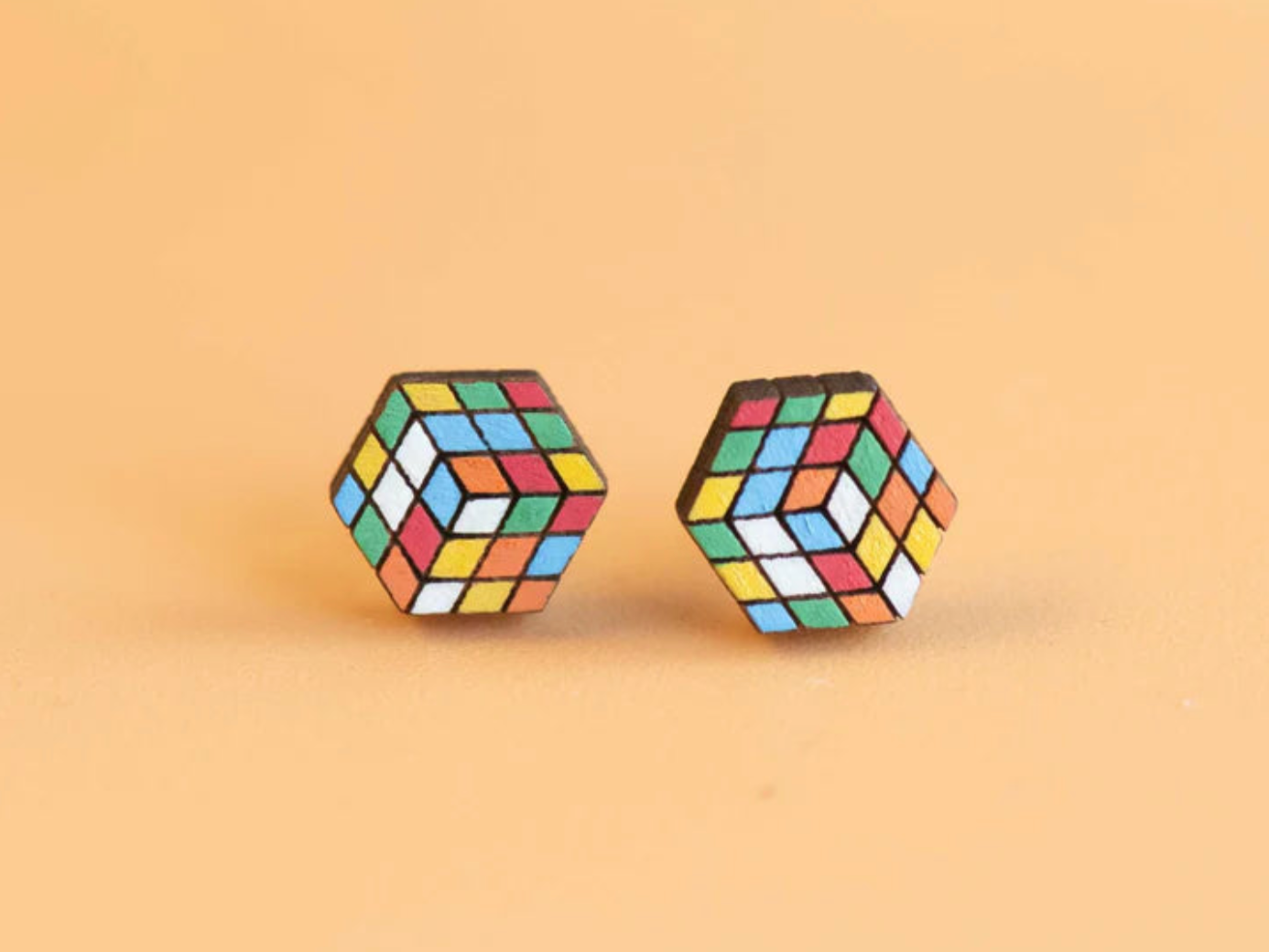 Photo of Rubik's cube earrings, which are flat wooden hexagons printed with a scrambled Rubik's cube design.