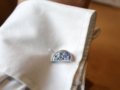 Photo of the protractor cufflink on a left shirt cuff. The protractor has marks at 45°, 90° and 135°.