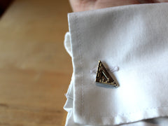 Photo of the set square cufflink on a right cuff. The set square has ruler notches along both the shorter sides, and one side has marks labelled 0 and 1.
