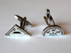 Photo of the pair of cufflinks, which are a metal set square and protractor