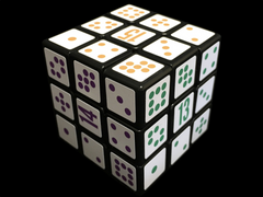 A photo of the Grime Cube solved for colour. The faces numbered 14 (purple), 15 (orange) and 13 (green) are visible, and the cube is white with these numbers in the centre of each face, and the remaining squares containing 1-8 dots in standard dice configurations, in some order around each face