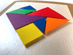 Photo of the rainbow tangram card from a low angle, showing that the pieces are raised slightly from the front of the card.