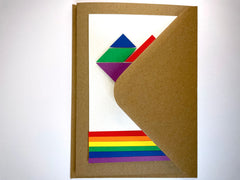 Photo of the rainbow tangram card inside its envelope, which is also brown.