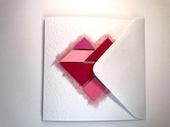 Photo of the pink tangram card in its envelope, which is white.